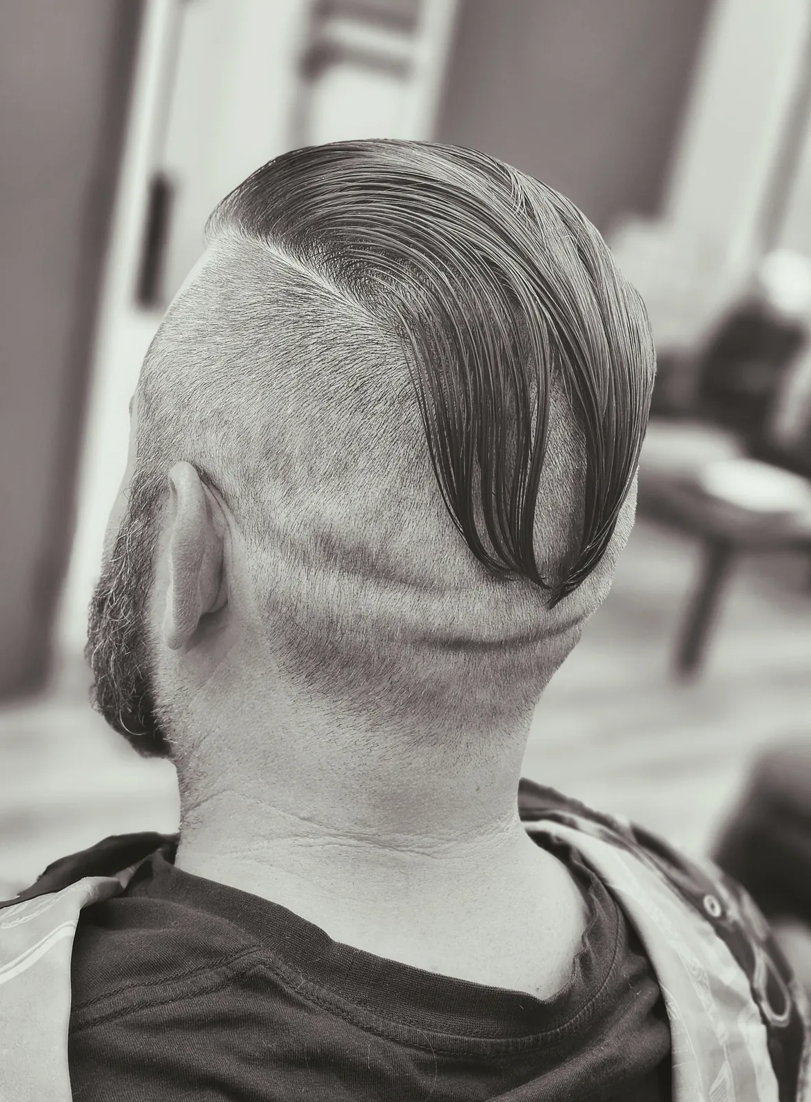 Men's disconnected undercut with long slick-back top and curved shaved hair design at Willow Road Barber Shop in Guelph