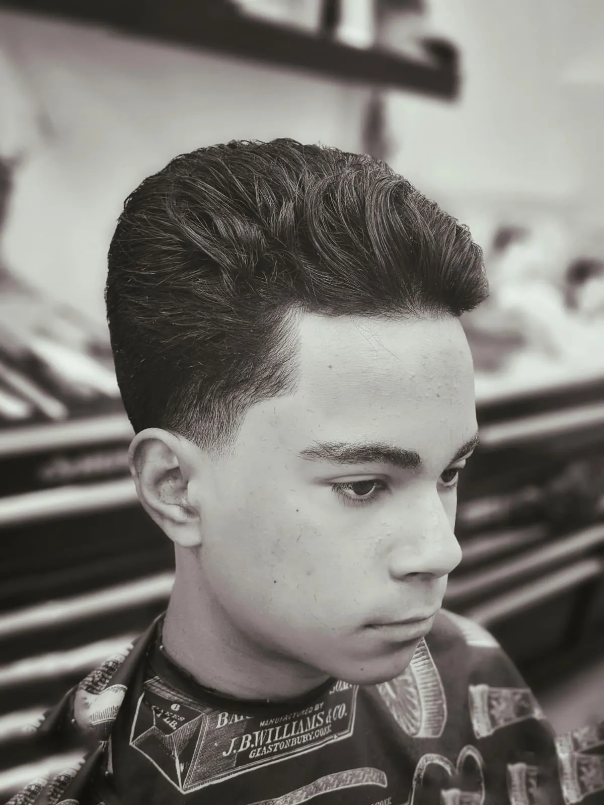 Teen low taper fade with swept-back pompadour at Willow Road Barber Shop in Guelph